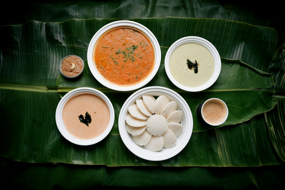 Idlis with sambar and chutneys served on a banana leaf