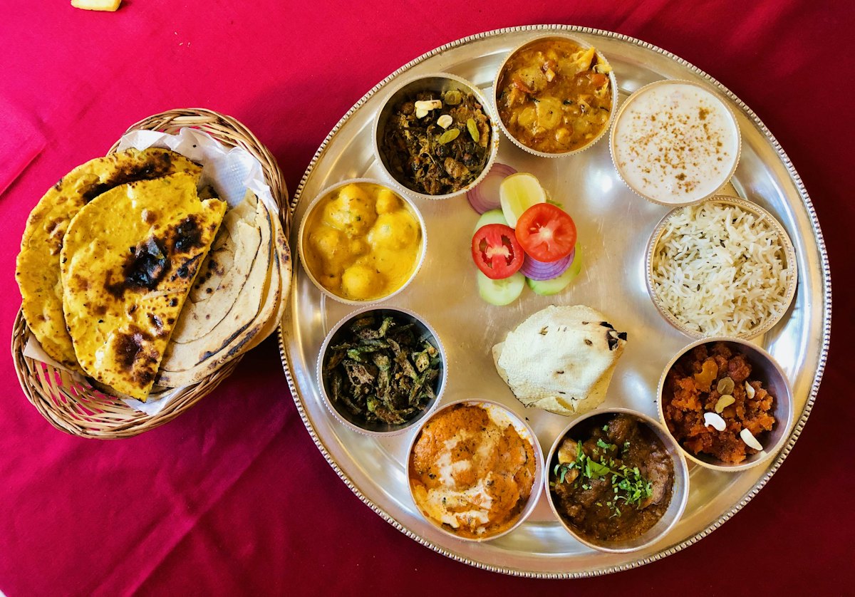 A steel thali with rice, chapati and an assortment of vegetarian dishes